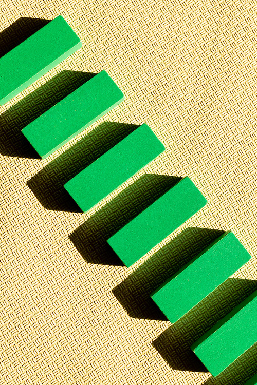 top view of diagonal row of green blocks on beige textured background