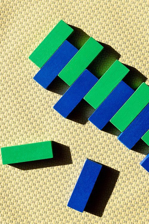 top view of green and blue blocks on beige textured surface with shadows
