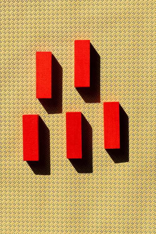 top view of bright red blocks on beige textured background with shadows