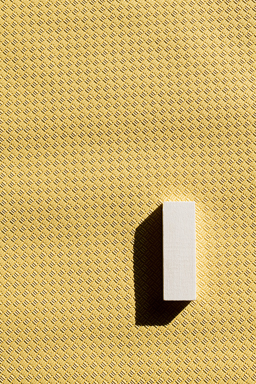 top view of white rectangular block on beige textured background with copy space