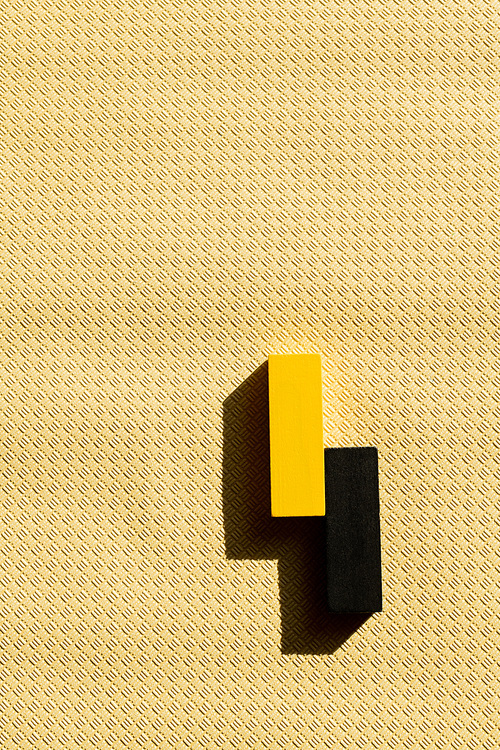 top view of black and yellow blocks on beige textured background with copy space