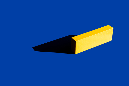 bright yellow tetragonal block on blue background with shadow, ukrainian concept