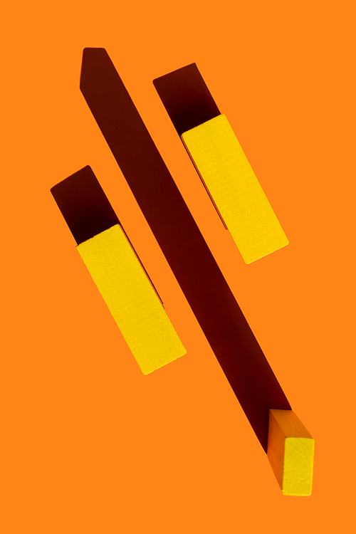 top view of yellow quadrangular blocks on bright orange background with shadows