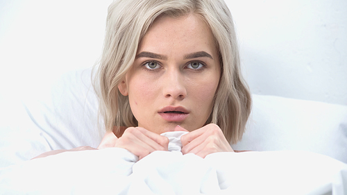 young afraid woman covering with blanket in bed