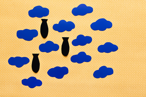 Top view of carton clouds and paper bombs on textured yellow background