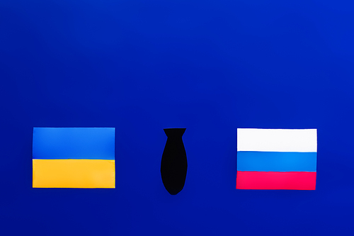 Top view of paper bomb between ukrainian and russian flags on blue background