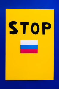 Top view of stop lettering and russian flag on blue and yellow background