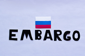 Top view of russian flag and embargo lettering on white background, war in ukraine concept