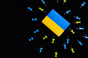 Top view of ukrainian flag near push pins isolated on black