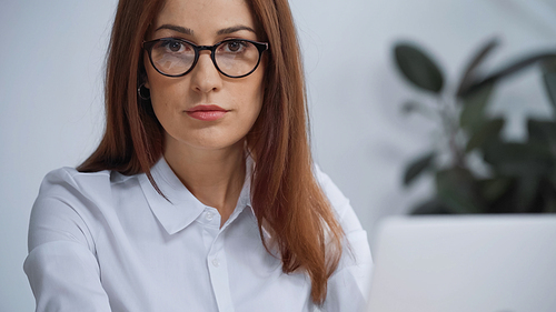 brunette businesswoman in eyeglasses  while working in office