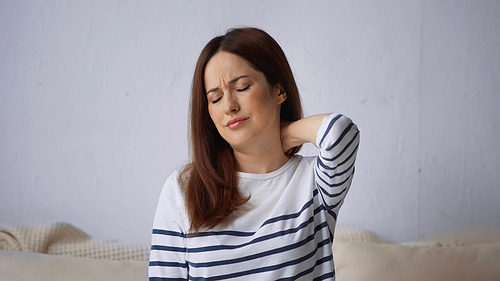 woman with closed eyes frowning while feeling pain in neck