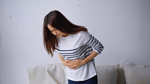 upset woman touching belly while suffering from stomach pain