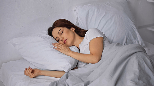 brunette woman sleeping on bed in morning
