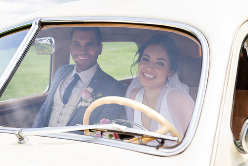 Smiling bride and groom  from retro car