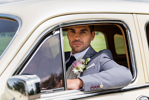 Elegant groom  in vintage car
