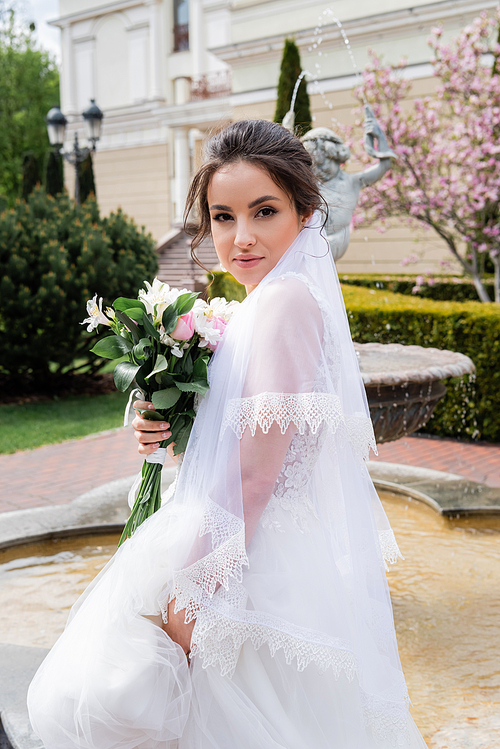 Pretty bride with bouquet  near fountain