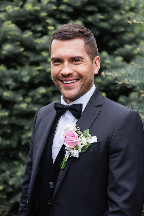 Groom in suit smiling at camera in park