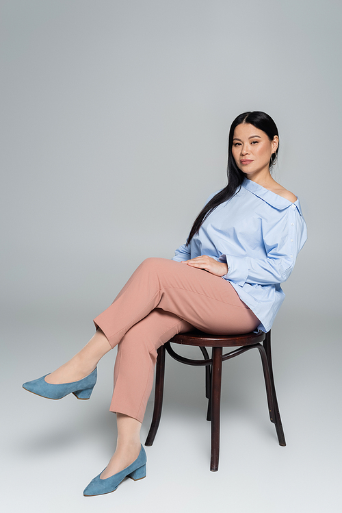 Stylish asian woman positing on chair and  on grey background