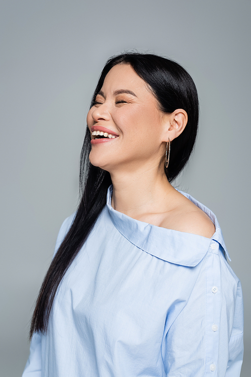 Portrait of asian woman with closed eyes laughing isolated on grey