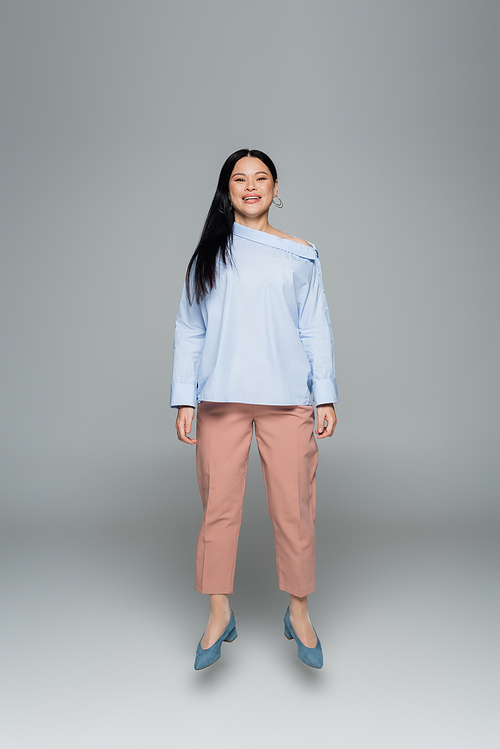 Smiling asian woman jumping and  on grey background