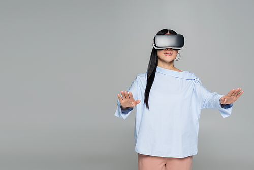 Woman in vr headset playing video game isolated on grey