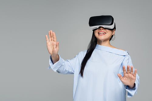 Cheerful woman gaming in vr headset isolated on grey