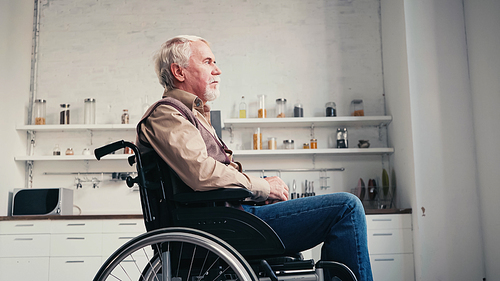 side view of bearded retired man in wheelchair looking away at home