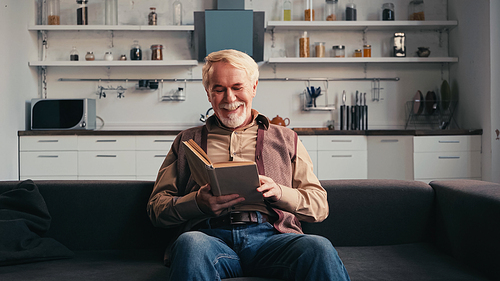 smiling senior man reading book at home