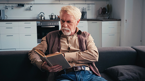 focused senior man reading book at home