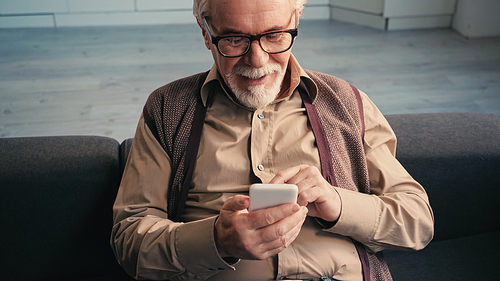 happy retired man in eyeglasses texting on smartphone