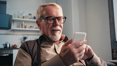 positive pensioner in eyeglasses using mobile phone