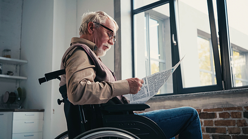 . senior man in wheelchair reading newspaper