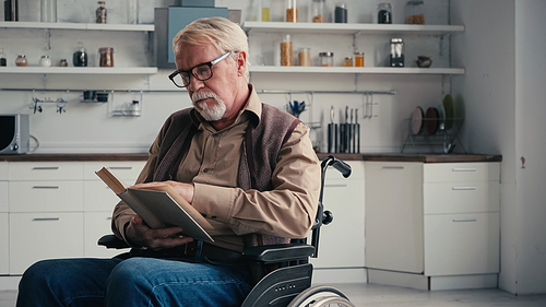 disabled senior man in wheelchair reading novel