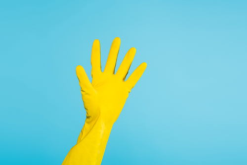partial view of woman wearing yellow rubber glove isolated on blue