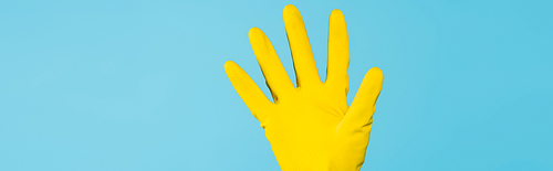 cropped view of female hand in yellow rubber glove isolated on blue, banner