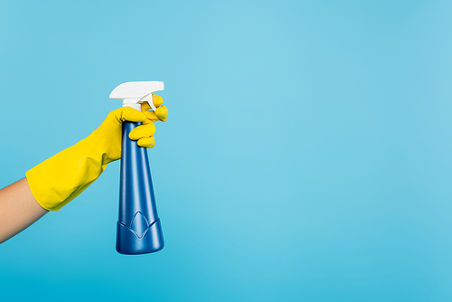partial view of woman in yellow rubber glove holding spray bottle with detergent isolated on blue