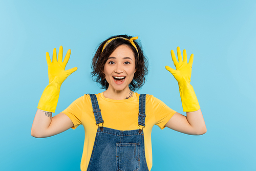 cheerful housewife in yellow rubber gloves  isolated on blue