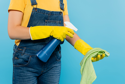 cropped view of housewife spraying cleanser on rag isolated on blue