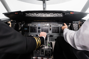 cropped view of pilots using yoke and thrust lever in airplane simulator