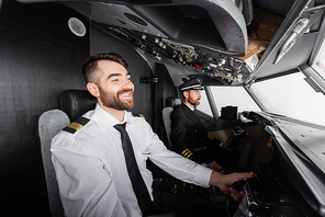 smiling co-pilot using yoke near captain while piloting in airplane simulator