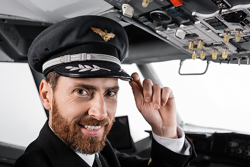cheerful pilot adjusting cap and  in airplane simulator