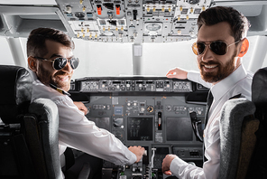happy pilots in sunglasses and uniform  in airplane simulator