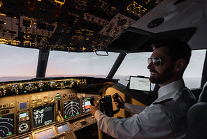 cheerful pilot in sunglasses using yoke while piloting in evening