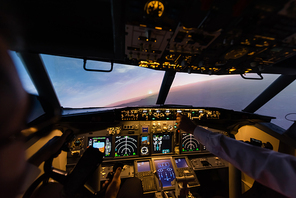 cropped view of professionals piloting airplane in evening