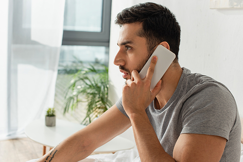 Side view of bearded man talking on mobile phone at home