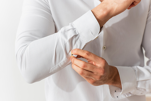 Cropped view of man buttoning sleeve of white shirt