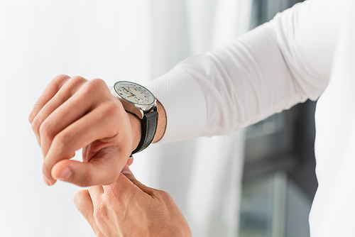 Cropped view of businessman wearing wristwatch at home