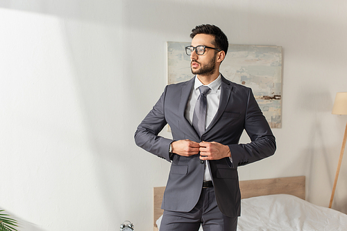 Young businessman in eyeglasses wearing jacket at home