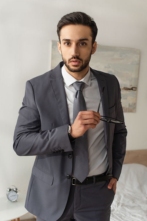 Young businessman holding eyeglasses and  in bedroom