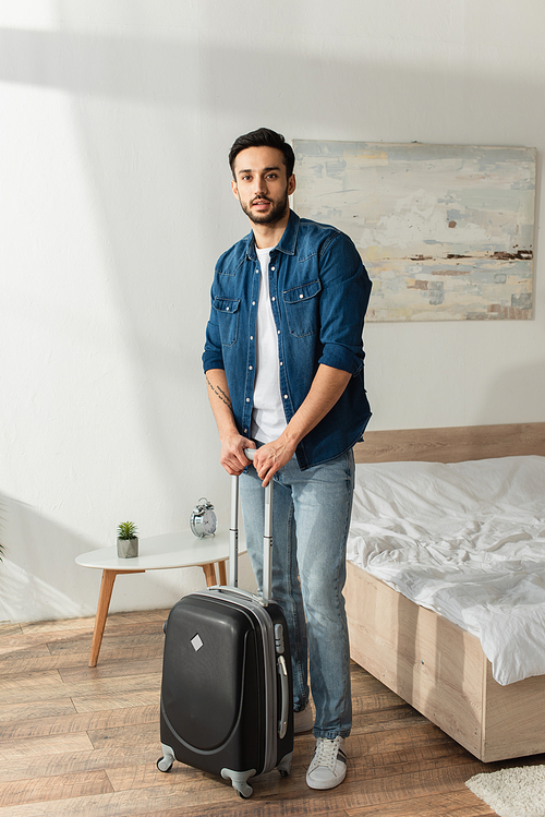 Young man with suitcase  in bedroom